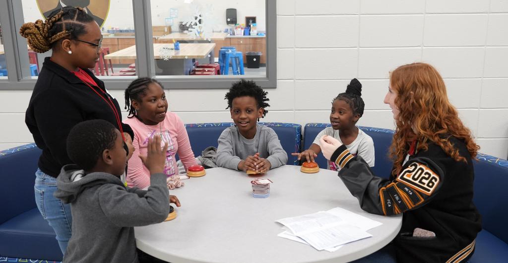High school students play a board game with elementary students