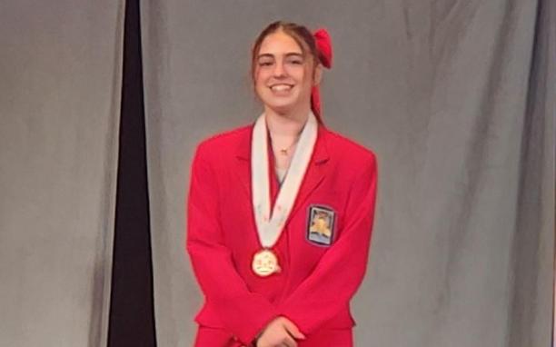 Avery Waszo standing on podium with award medal around her neck.