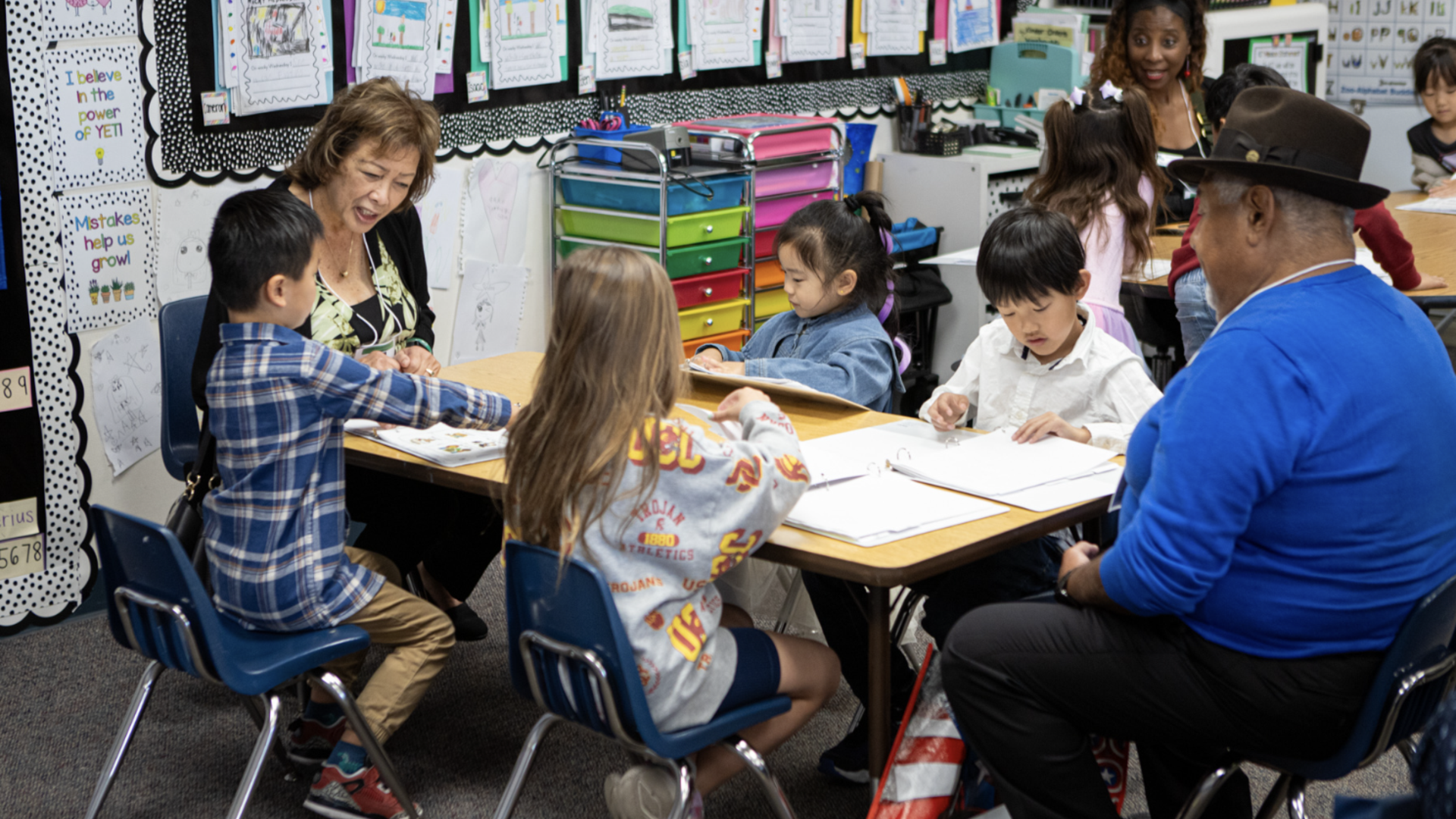 Children and adults engaged in an educational activity at a classroom table.
