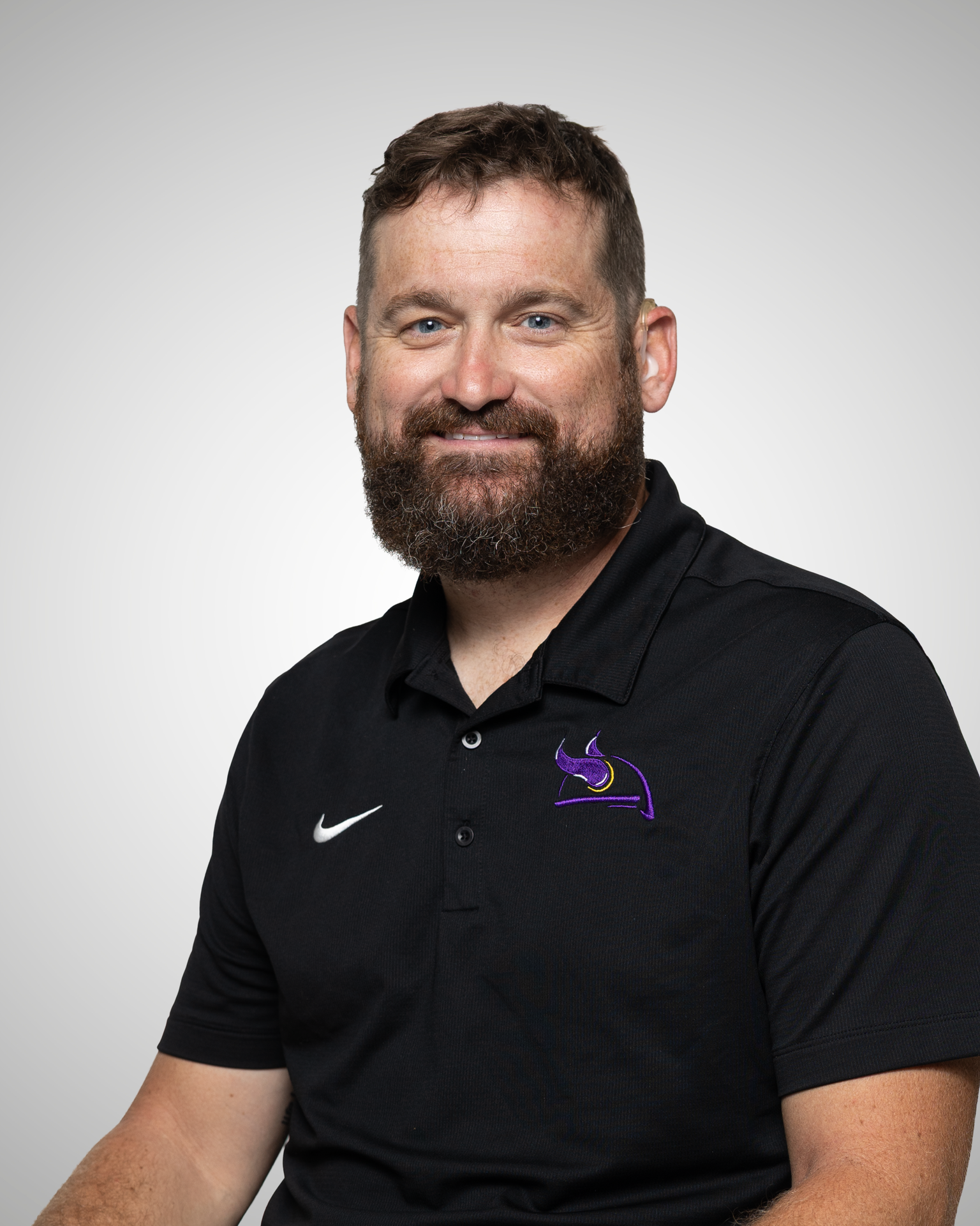 Man with a beard wearing a black polo shirt with the Tennessee School for the Deaf logo.