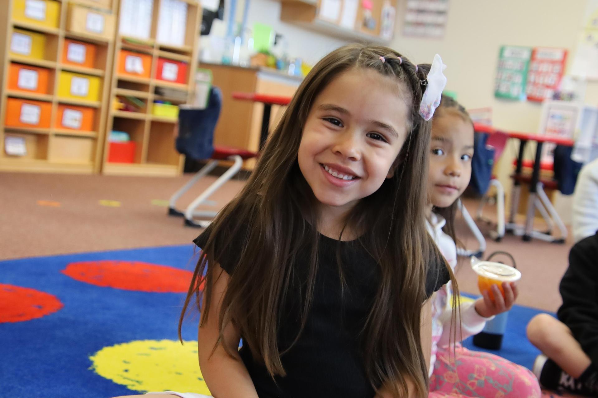 elementary school girl smiling for the camera in a classroom