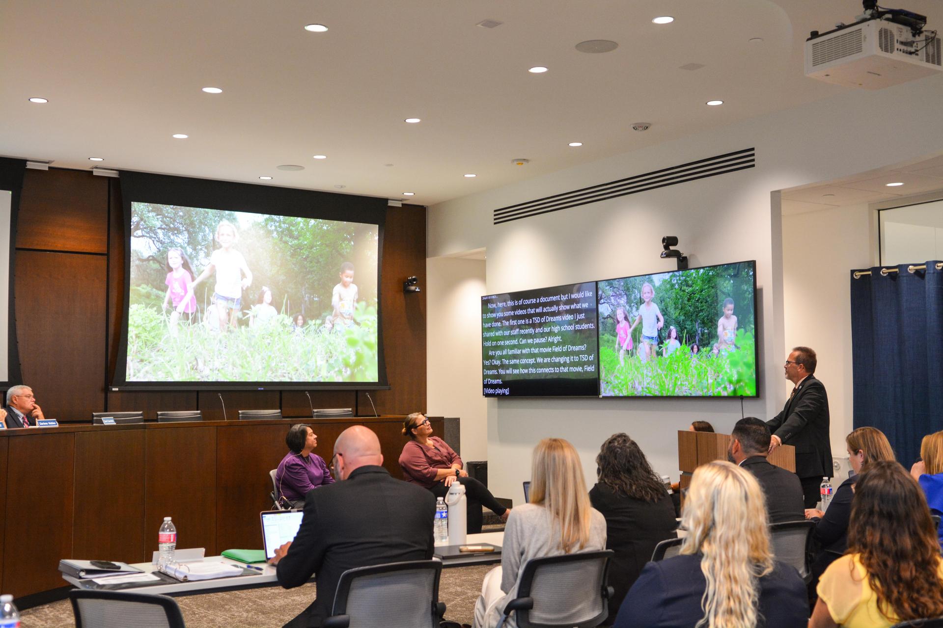 Board watches presentation with children on screen.