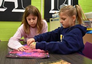 two girls tying a piece of string