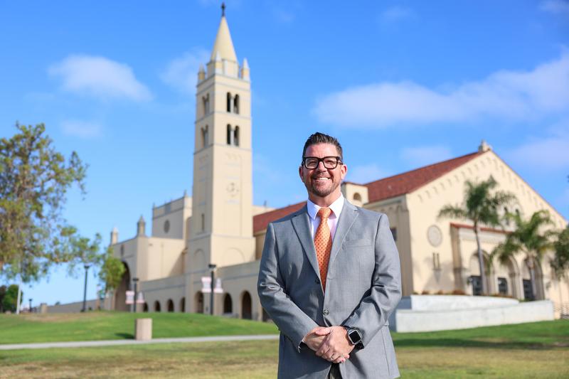 Tim Floyd smiling in front of Huntington Beach High School campus