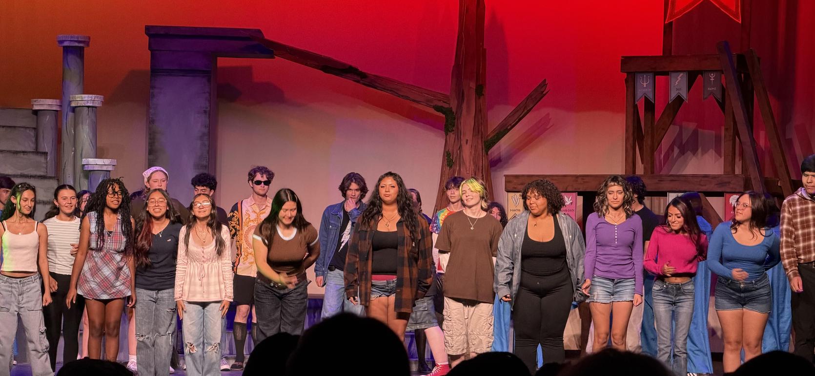 A group of diverse performers on stage, bowing at the end of a theater production.