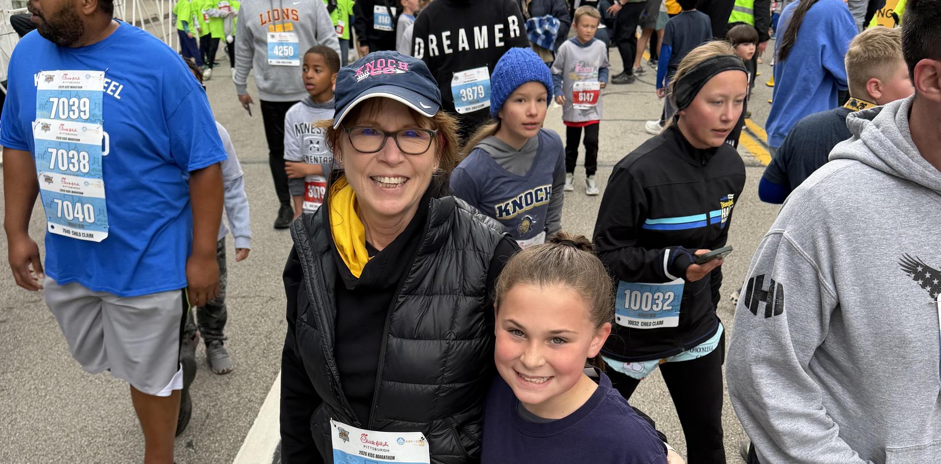 Woman posing with a girl at a community race event, both smiling.