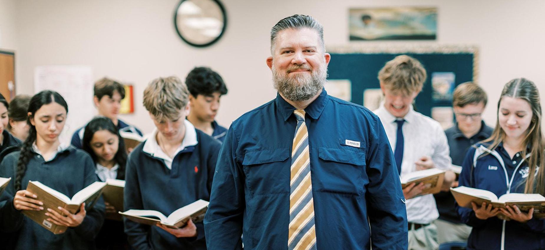 Teacher stands with high school students holding open books