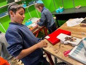 A third grade boy watches as his penny bridge collapses