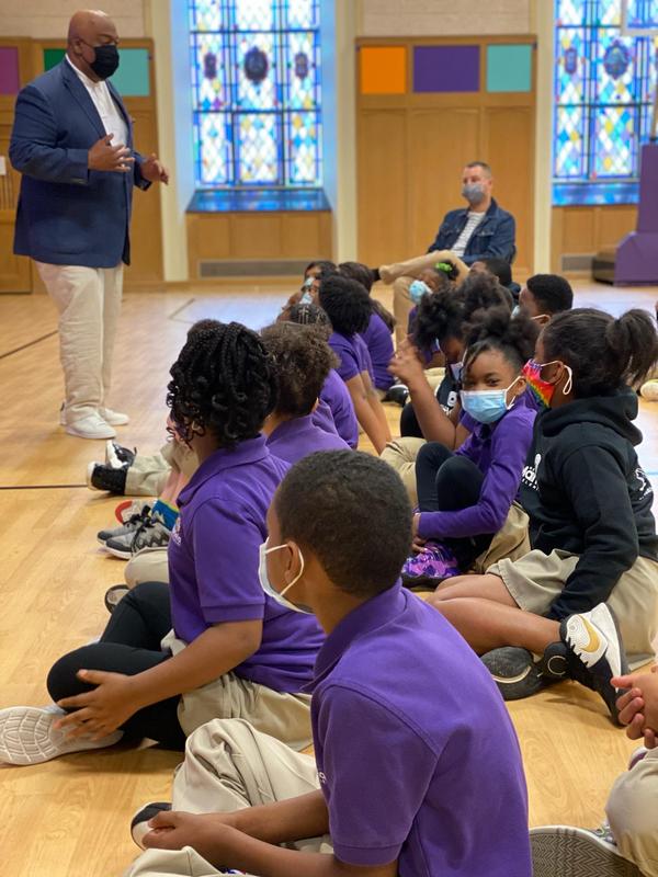 Scholars sit in the gym listening to a presentation