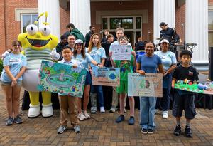 Students posing for picture with their Earth Day poster