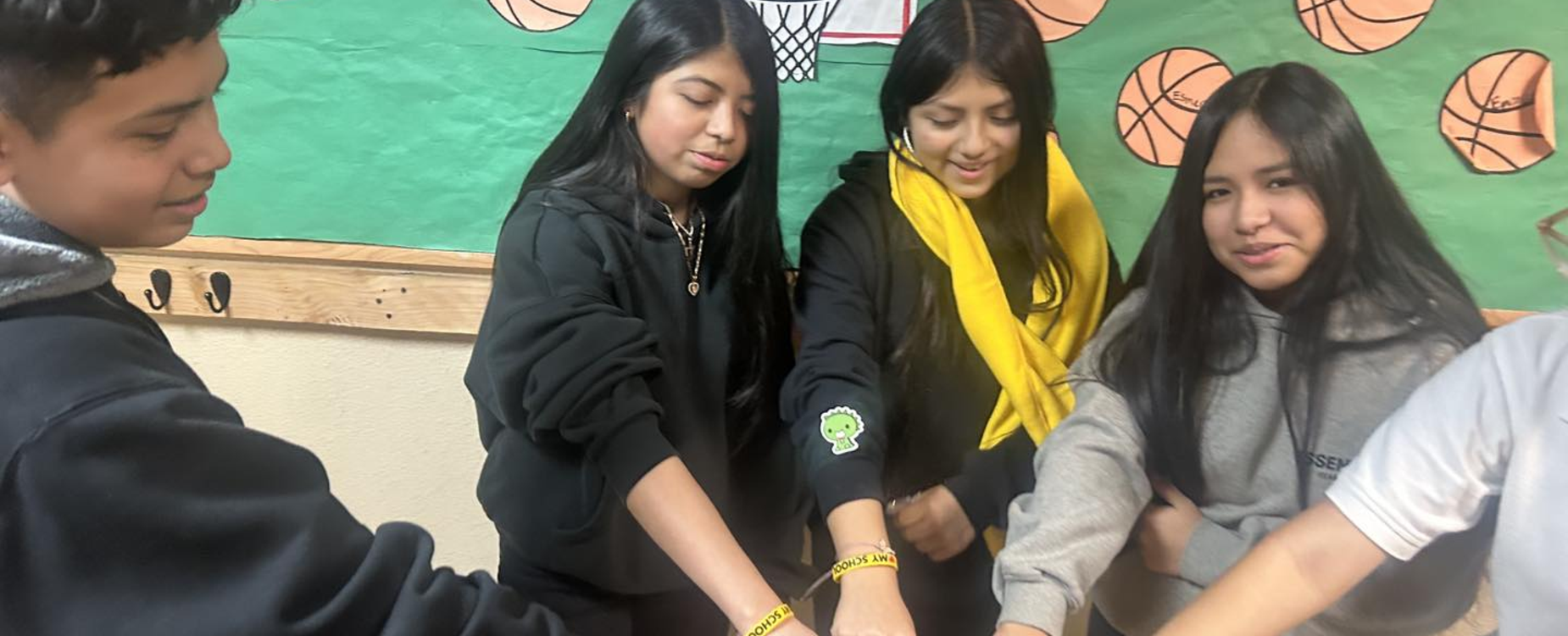 a group of students in a huddle showing off their wristbands