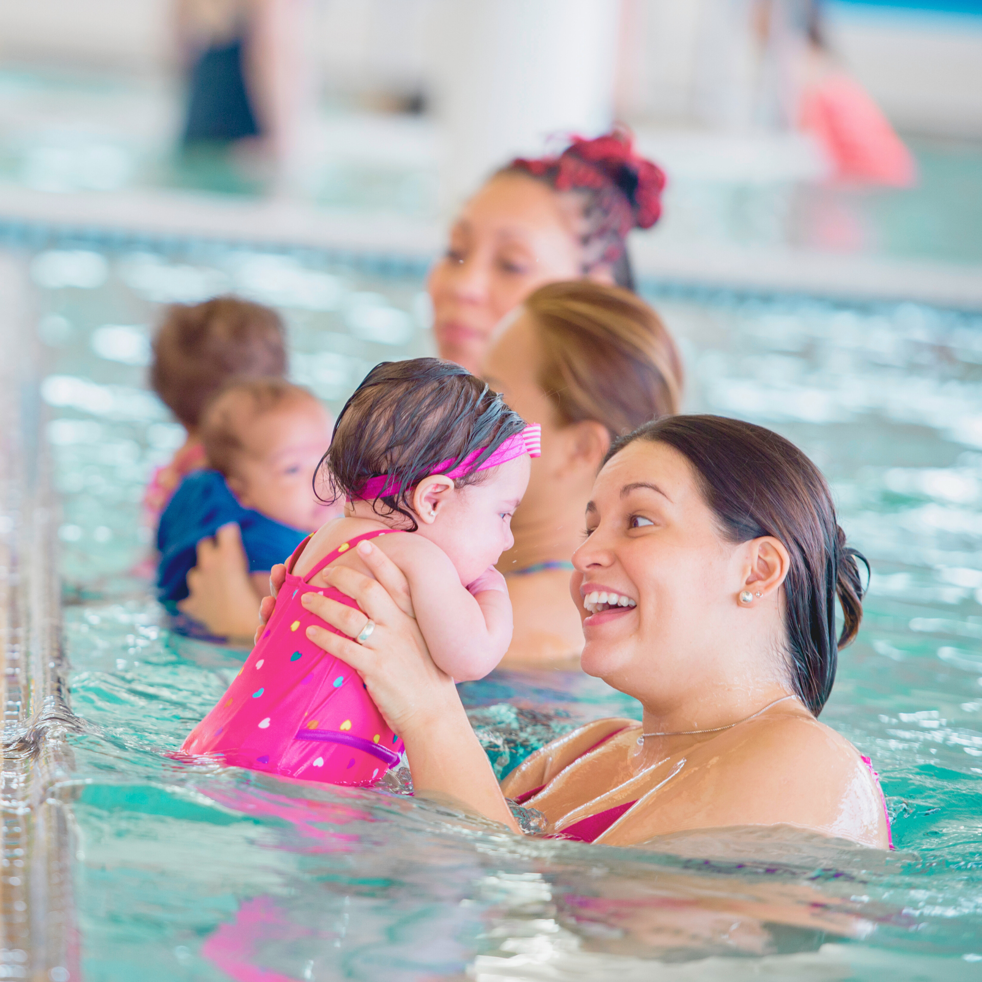 parent holding toddler in the pool