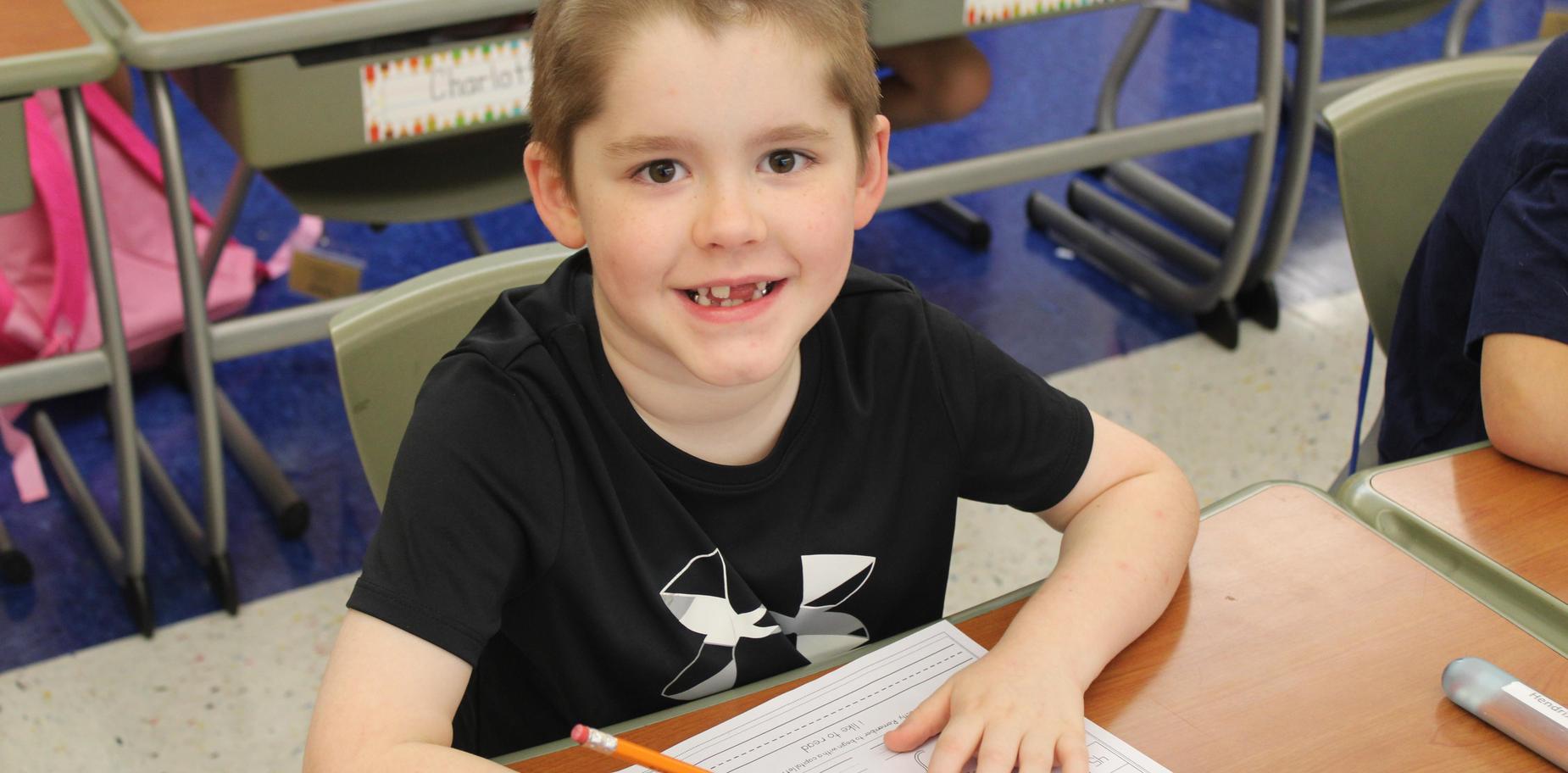 Boy with a pencil and paper, focused while working at his desk.
