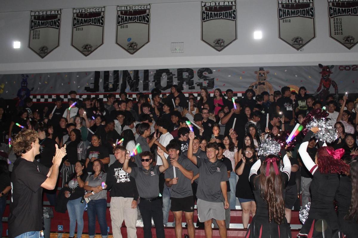 A group of students stand and wave lights during an assembly.