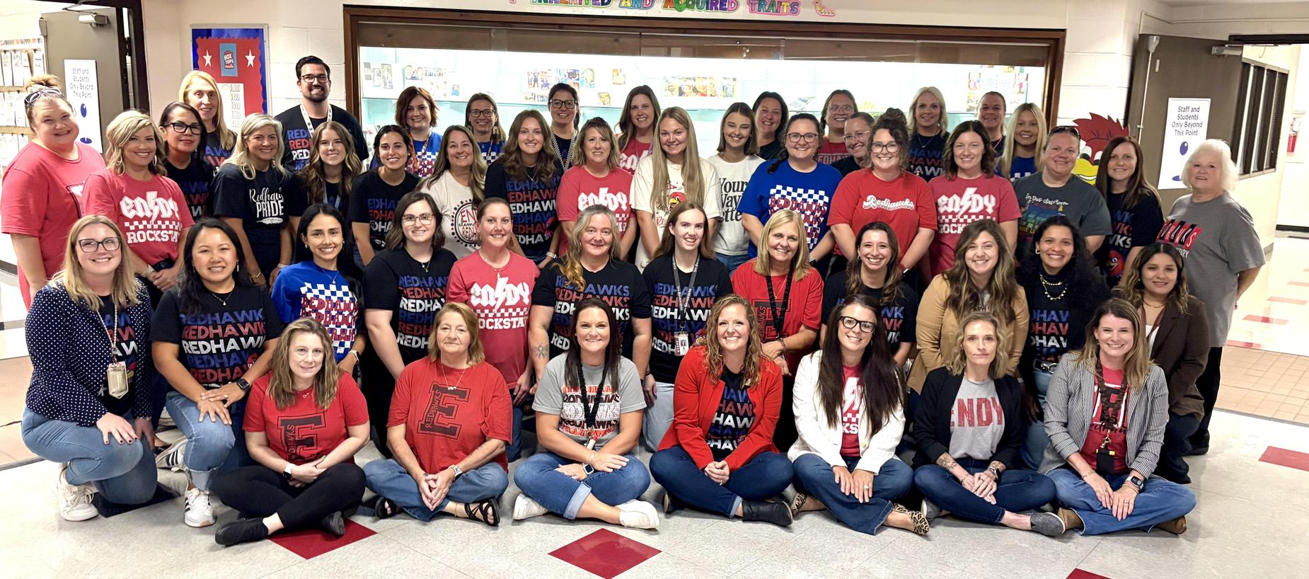 Group of educators and staff posing together in a school hallway.