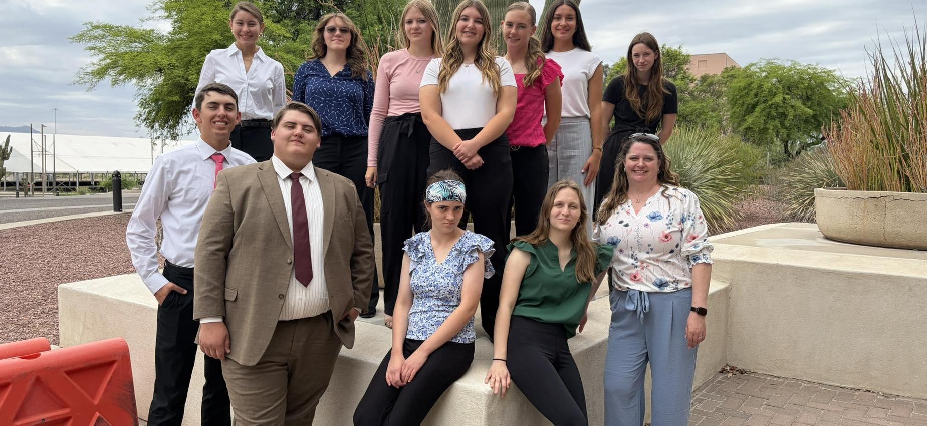 A group of professionals posing together outdoors in business attire.
