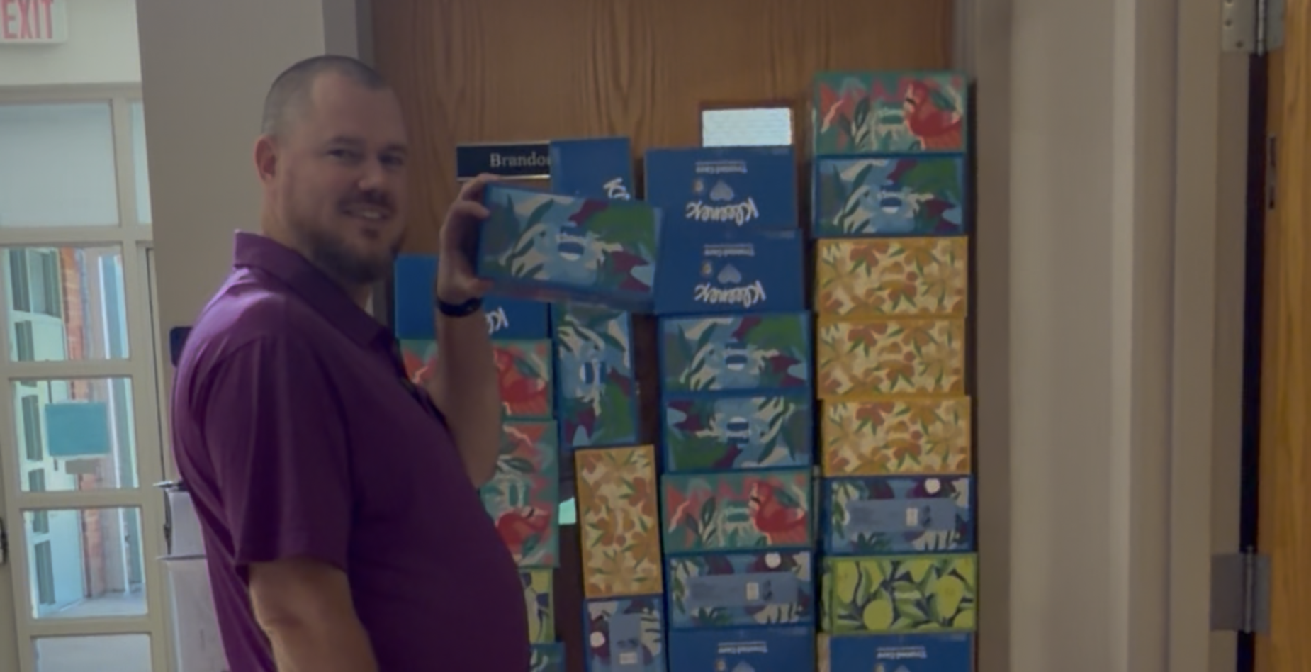 A man standing next to a wall covered with colorful boxes.