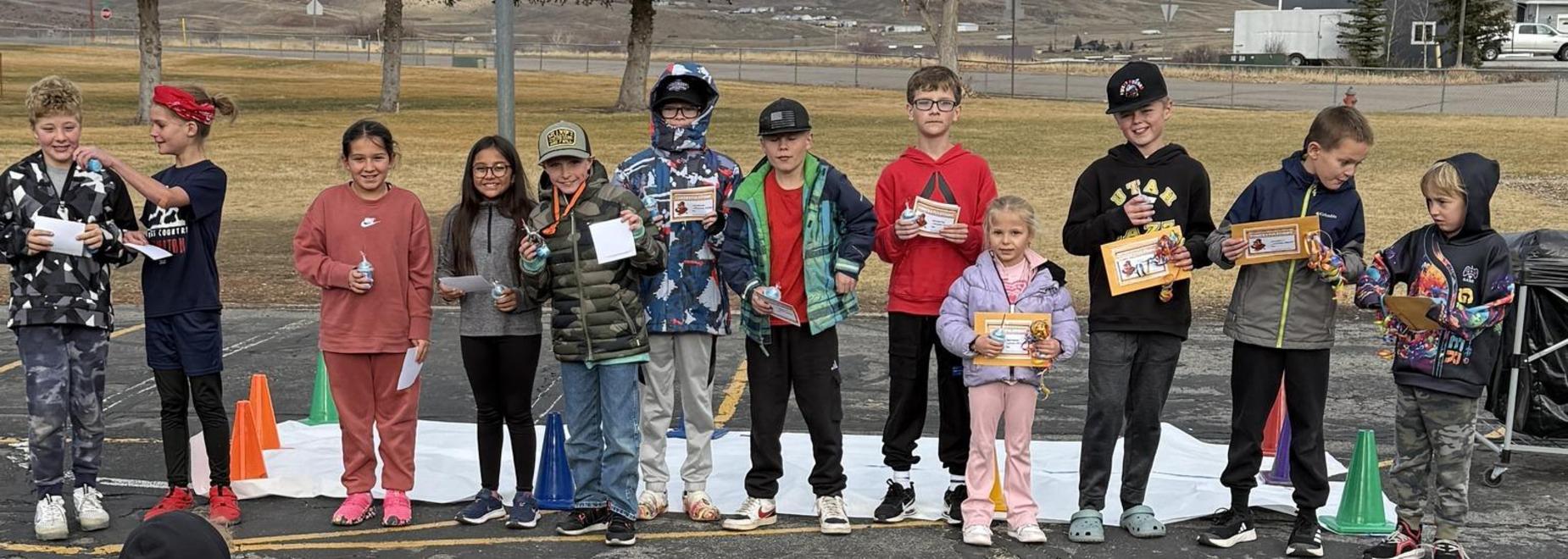 A group of children stands on stage holding awards, celebrating and smiling together.