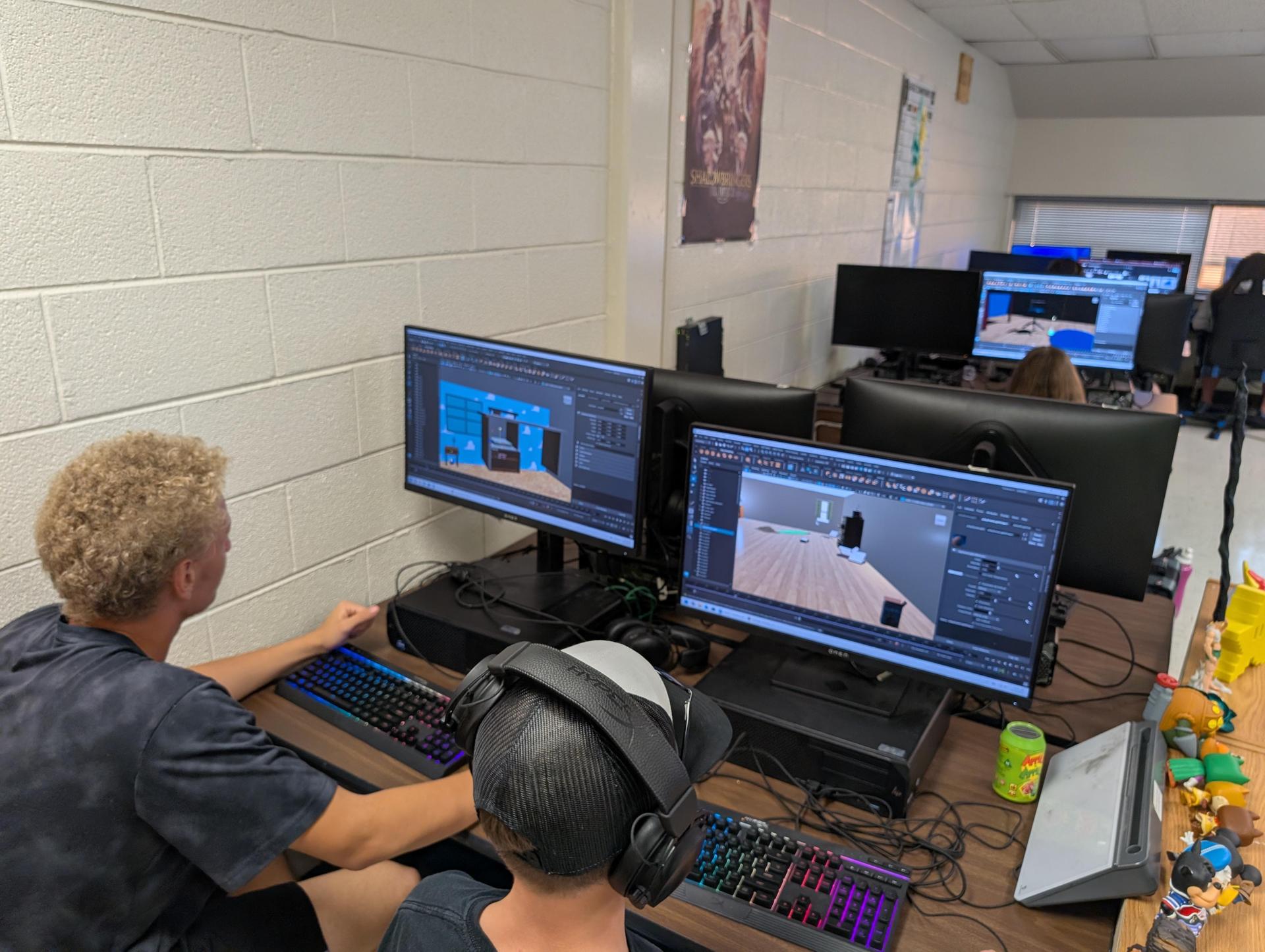 Students working on computers with dual monitors in a classroom setting.