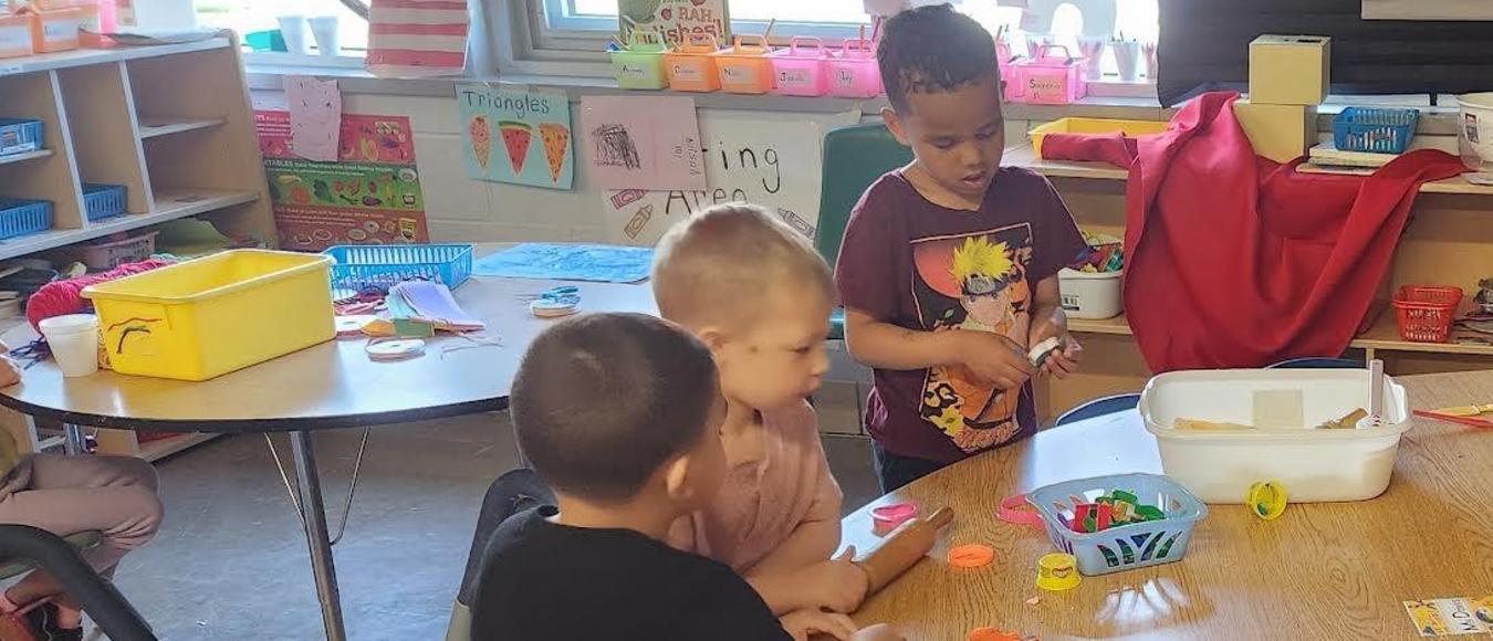 Children are sitting at a table playing with Play-Doh.