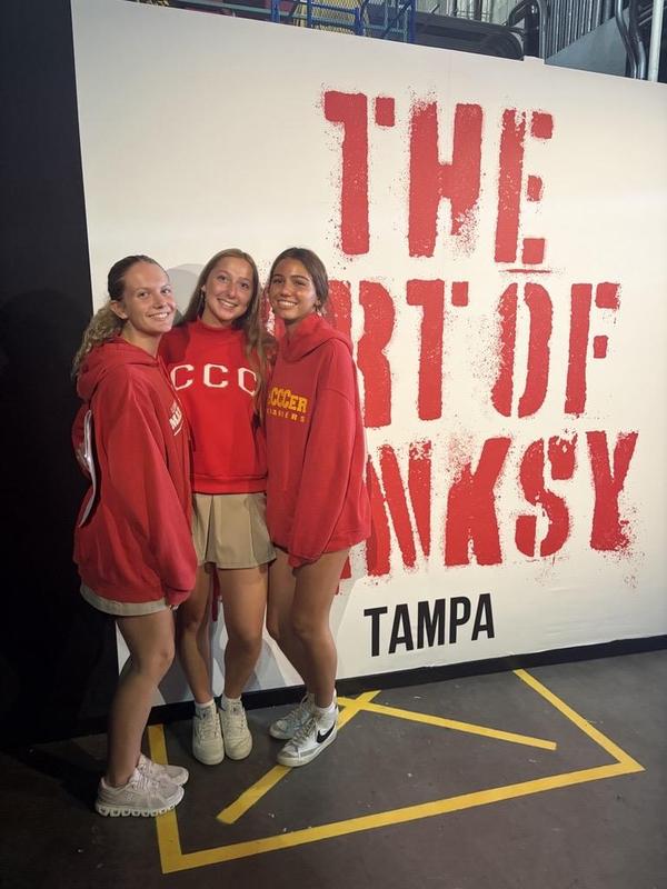 3 girls pose with "Art by Banksy" sign