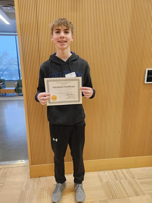 boy smiles holding certificate for winning