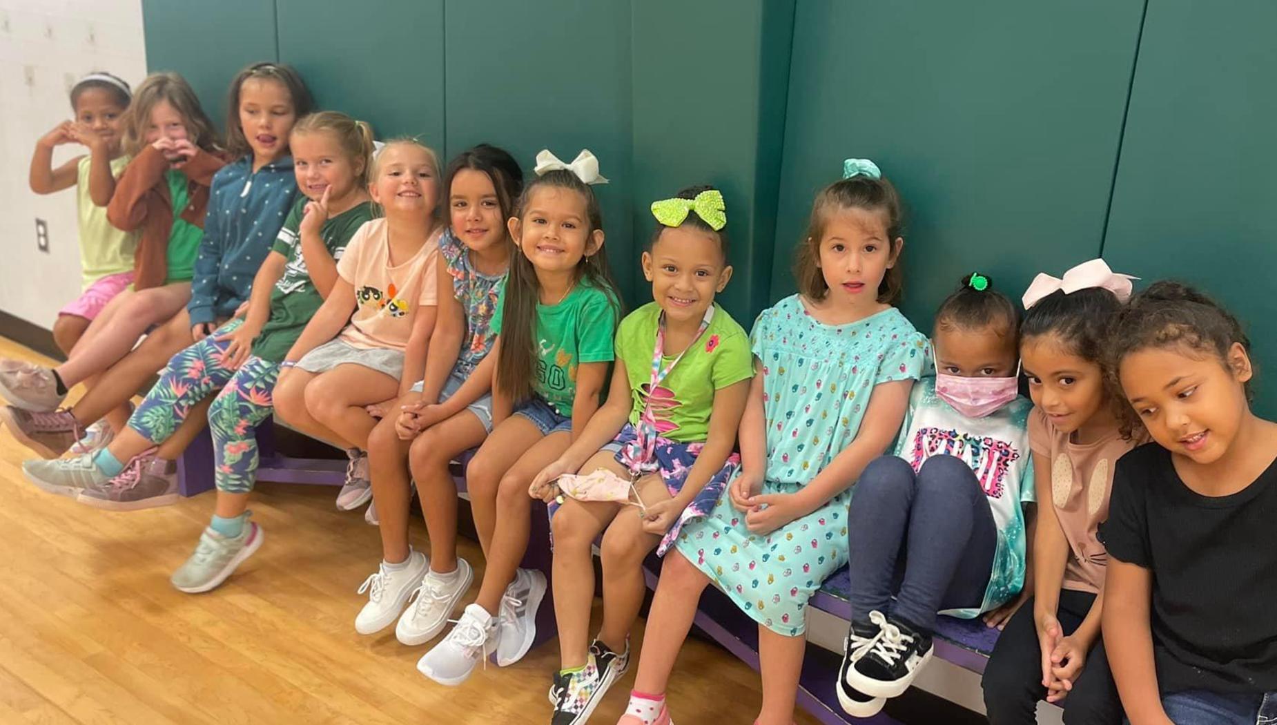 kinder girls wait on a bench in PE