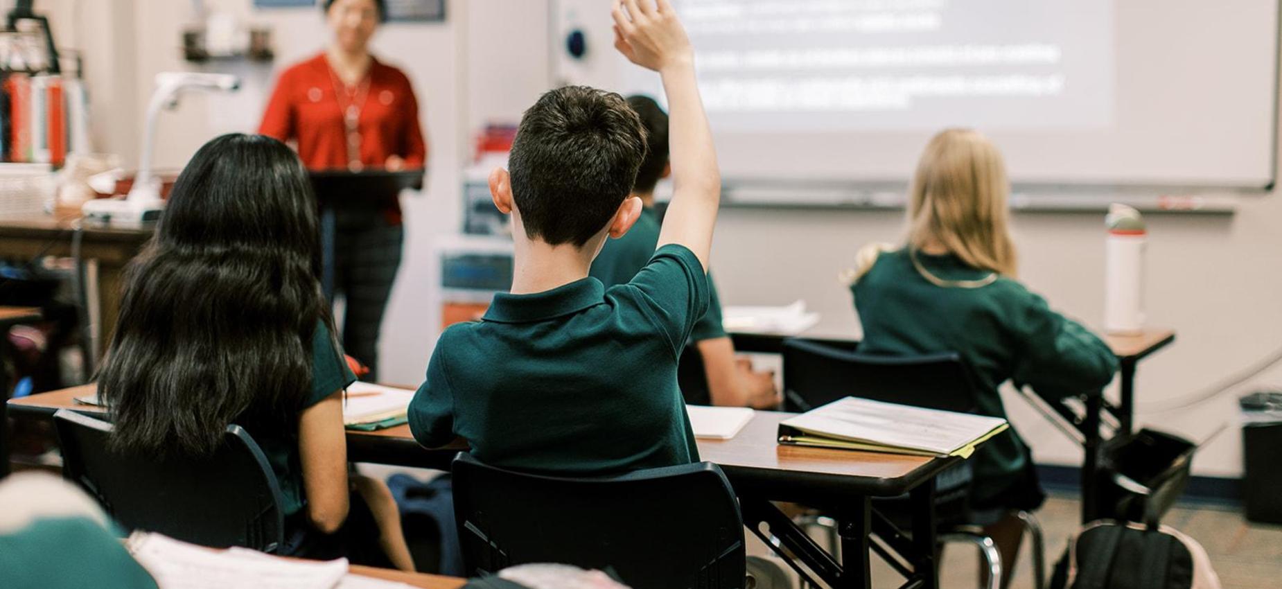 Students raise their hands as the teacher calls on them