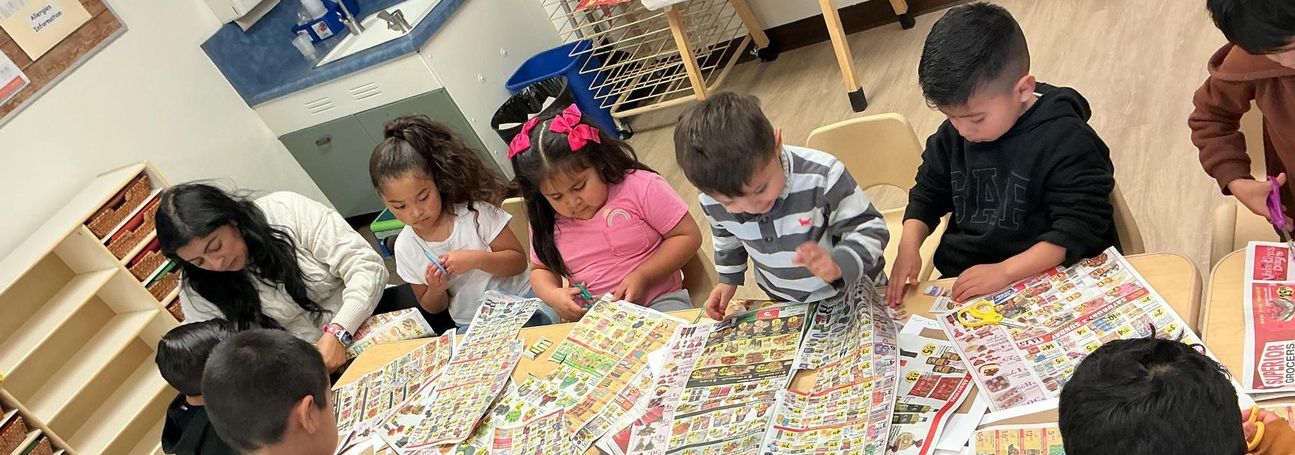 Students at table cutting newspaper