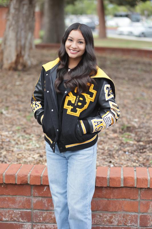 A female student from Santa Fe High School smiles at the camera while sporting her letterman jacket.