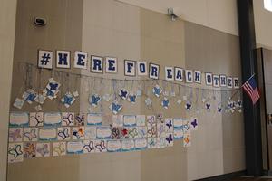 wall with hashtag here for each other written on it and hand decorated butterflies hanging down