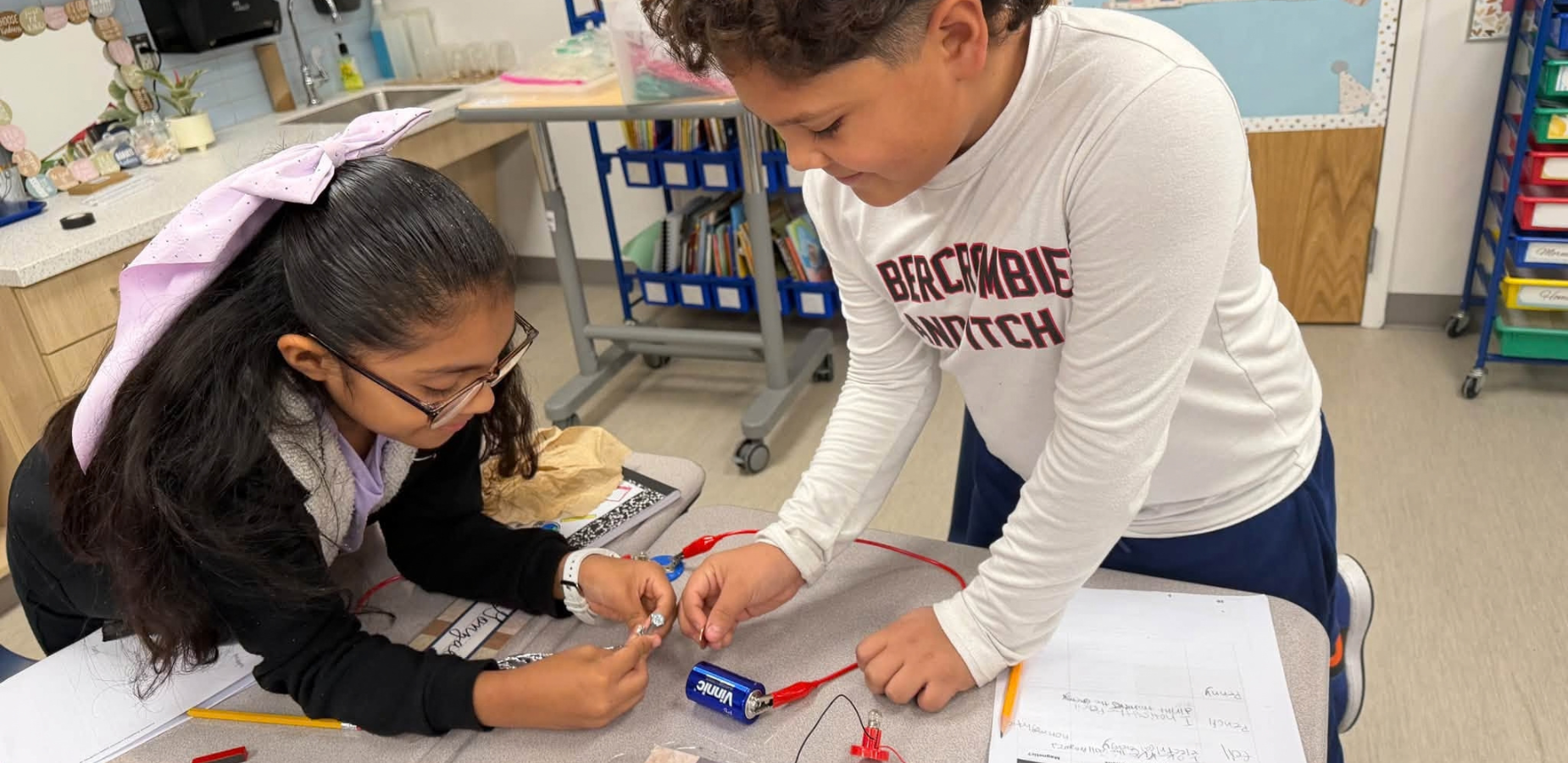 Two students work together on a hands-on science project at a table.