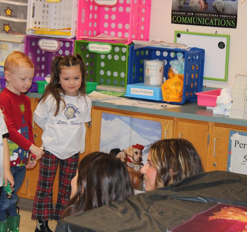 two preschoolers watching two middle schoolers