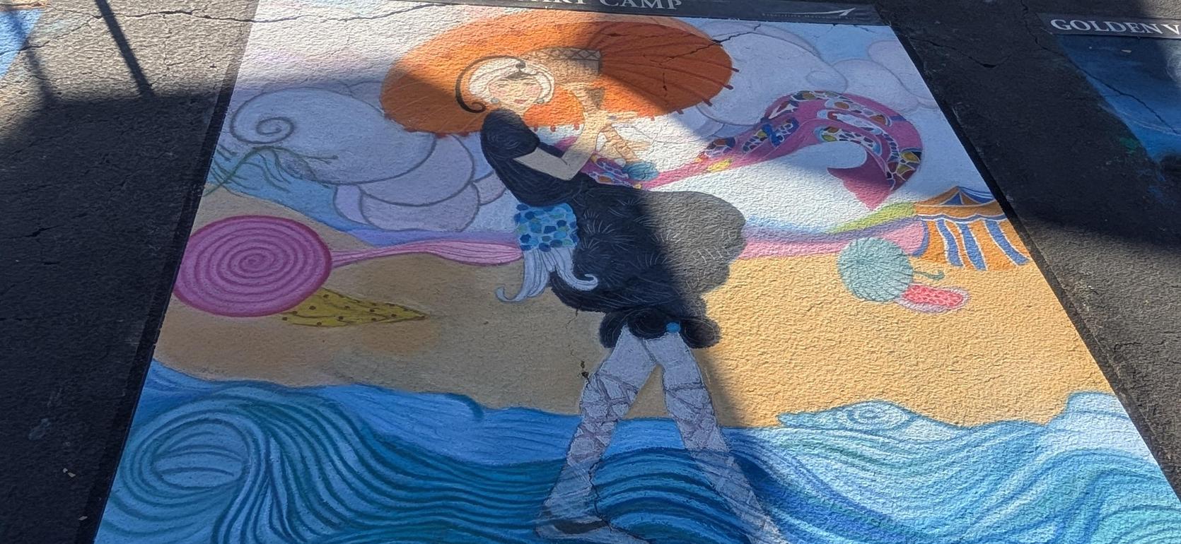 A colorful chalk mural featuring a figure against a beach scene, with vibrant swirls.