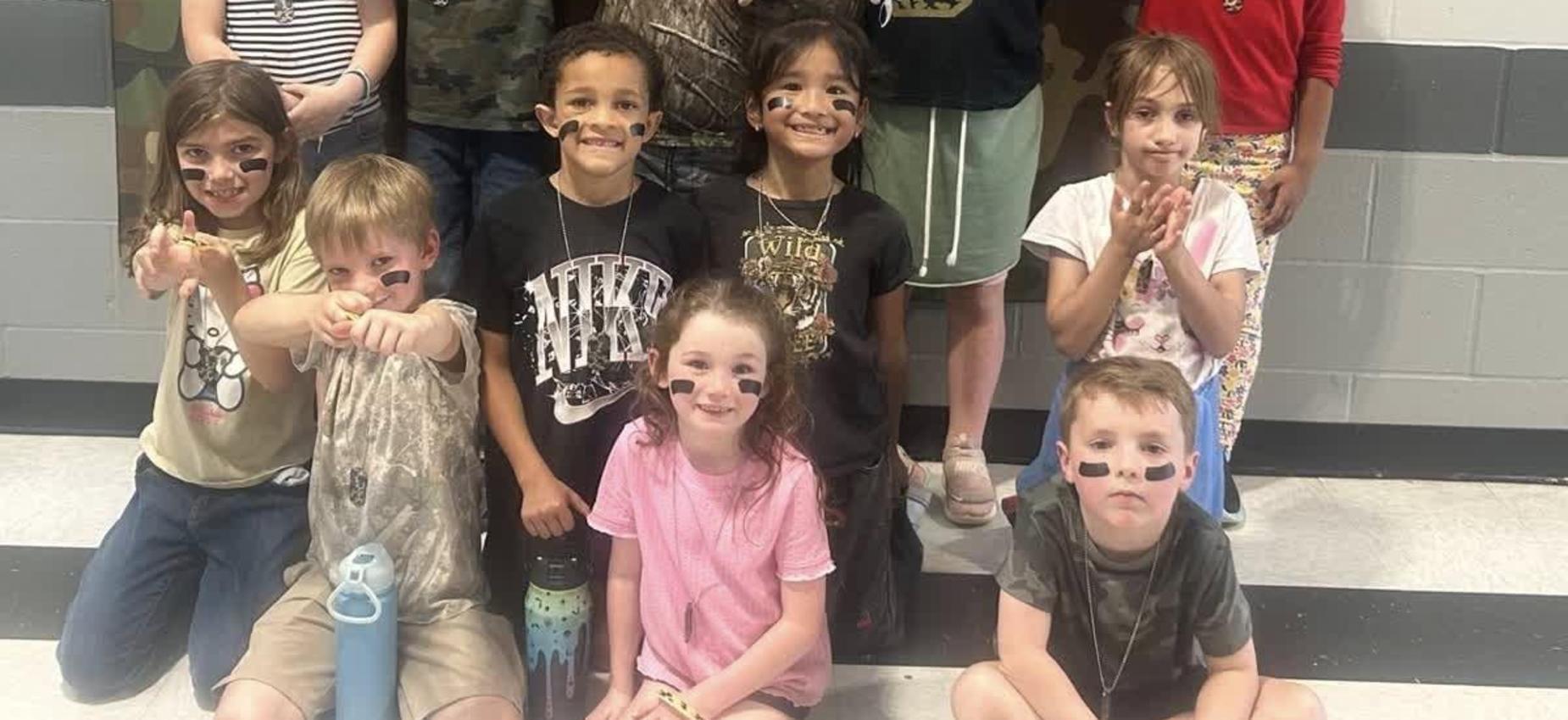 Group of children in camo clothing with face paint posing together.