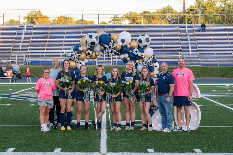 large group of girls in uniforms posing on a field