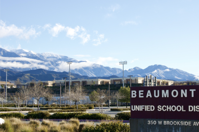 Sign reading Beaumont Unified School District in front of a snow capped mountain range