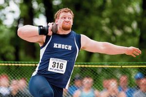 high school senior boy has shot put on shoulder about to throw