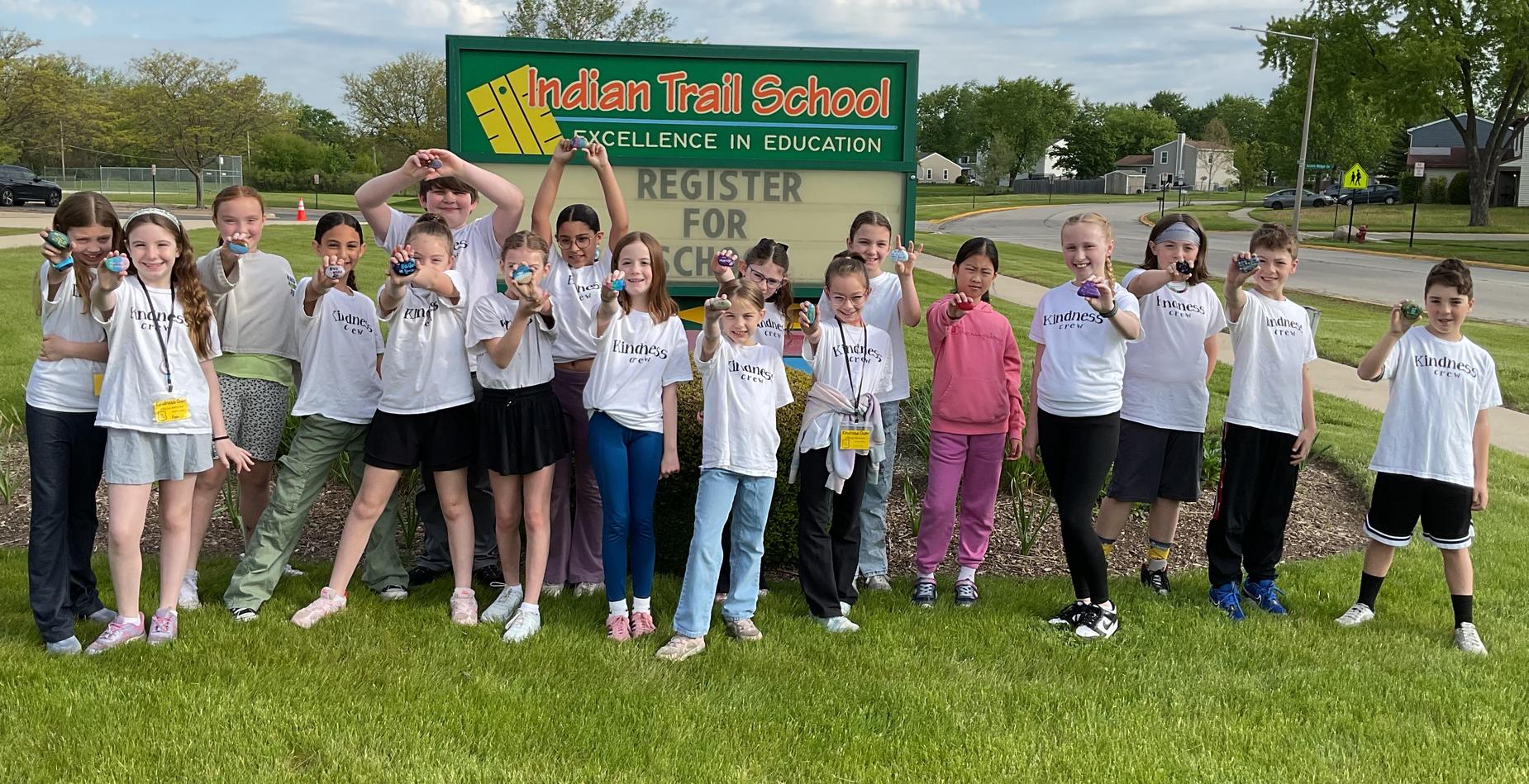 Kindness Crew group photo in front of the school sign