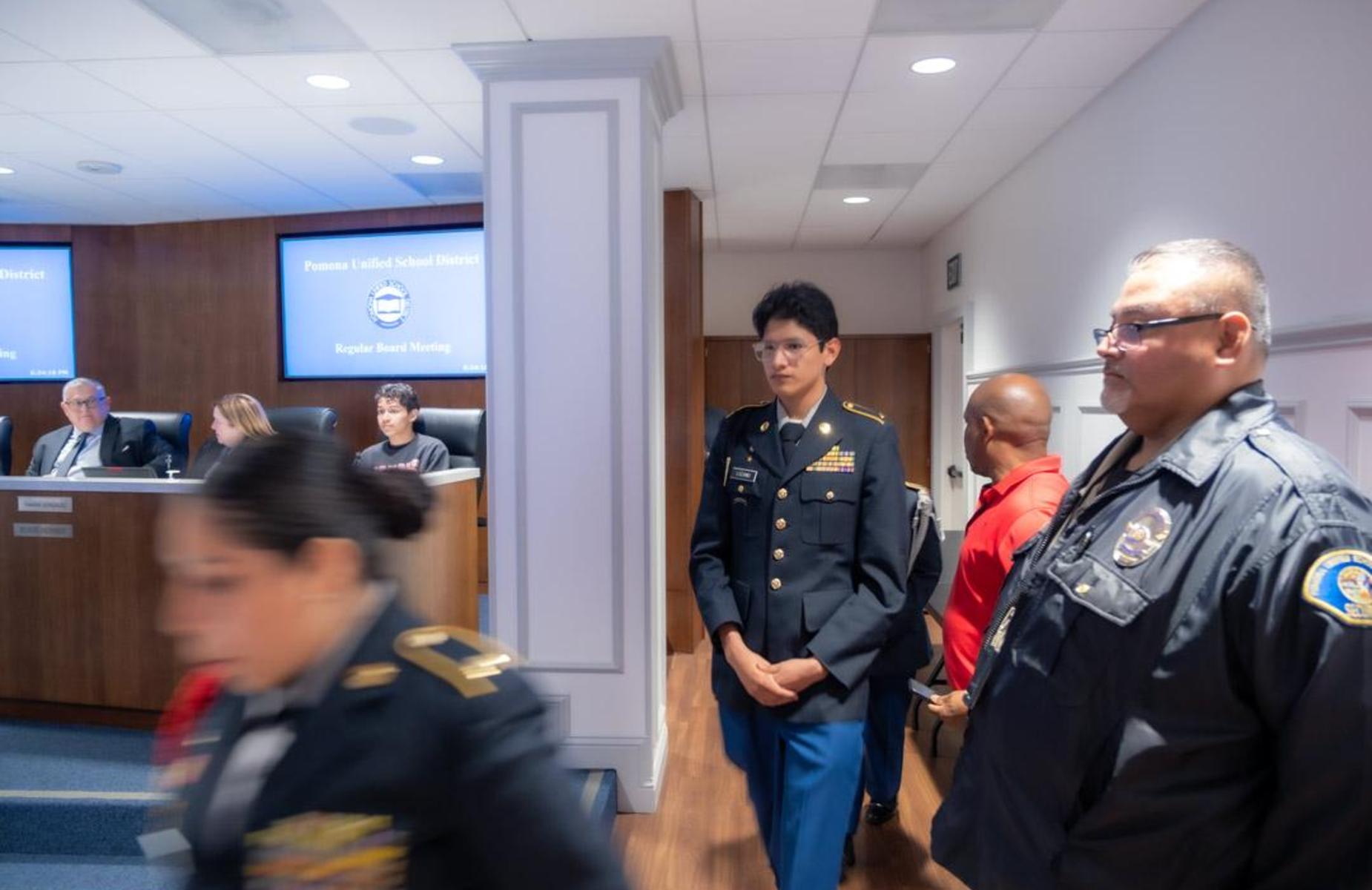 students in uniform walk to pudium