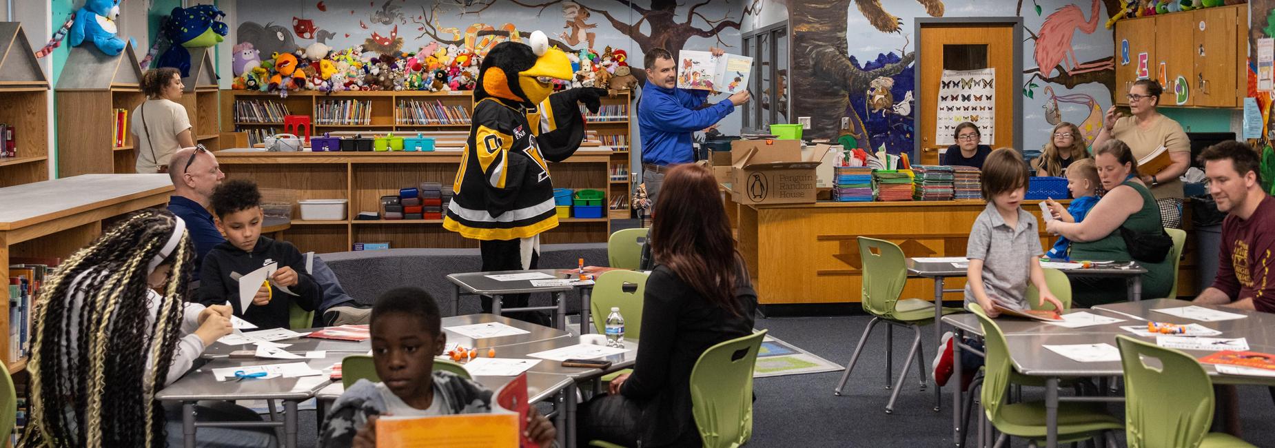 A guest reads a book to students and families
