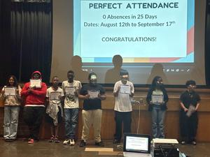 Students holding Perfect Attendance certificates on stage
