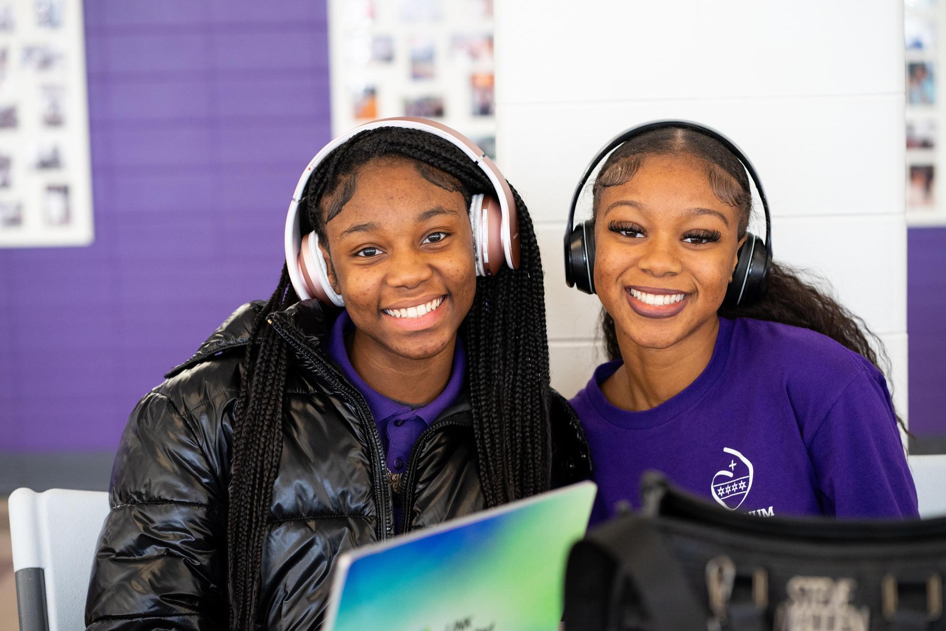 two girls wearing headphones smiling for the camera