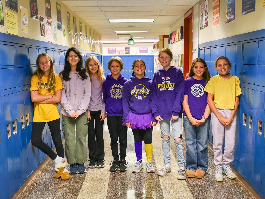 A group of students wearing spirit wear in front of the lockers in the school hallway.