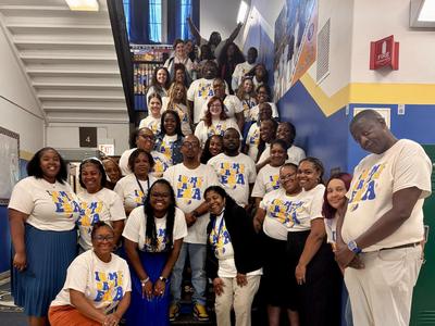 A group of educators poses together on a staircase wearing matching shirts.