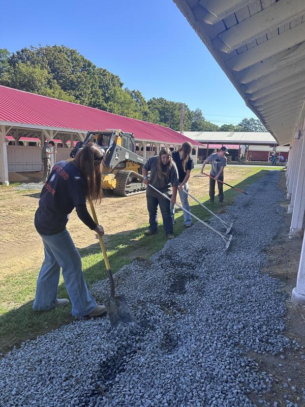 FFA students use rakes to spread stone at the Franklin County Fairgrounds