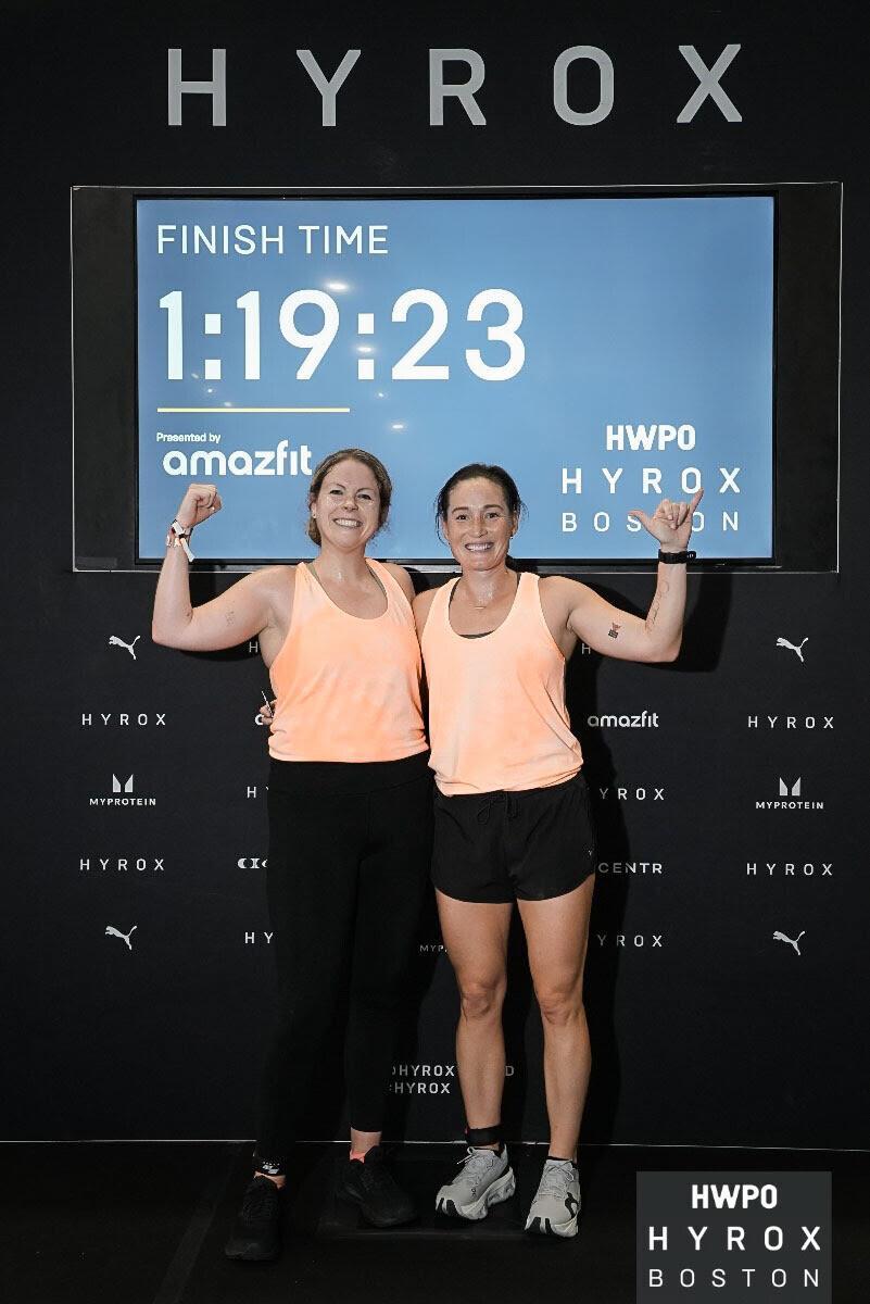 Two women standing in front of a sign