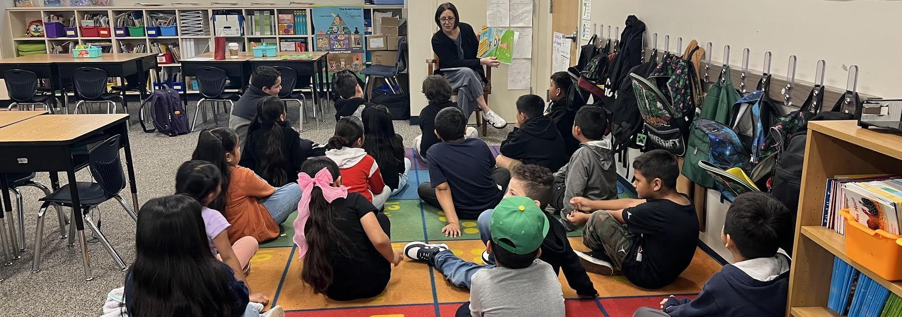 an adult reading to a group of students