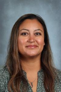 Friendly woman with long brown hair, wearing a green patterned blouse.