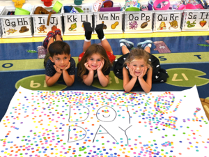 Three students laying on the floor with Dot Day Poster